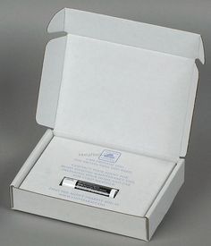 an open white box with a small electronic device in it's bottom corner on a gray background