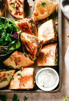 grilled fish and greens with ranch dressing on a baking sheet, ready to be eaten