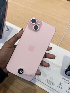 a person holding an iphone in their hand next to other phones on display at the apple store