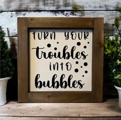 a sign that says turn your troubles into bubbles on it next to some potted plants