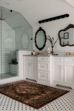 a bathroom with white cabinets and black and white flooring, two mirrors on the wall