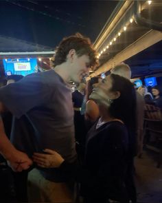 two people standing next to each other in front of a tv screen at a party