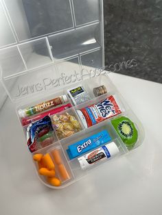 a plastic container filled with lots of different types of snacks and candy bar wrappers