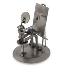 a metal sculpture of a person sitting in a chair with a wrench on his knee