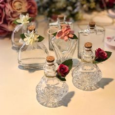 three glass bottles with flowers in them sitting on a table next to some other bottles