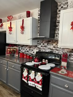 a black stove top oven sitting inside of a kitchen next to white cabinets and christmas decorations