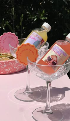 two bottles of soap sit in a wine glass on a table with other items nearby