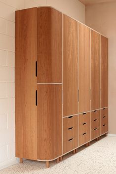 a large wooden cabinet sitting next to a white brick wall in an empty room with no people