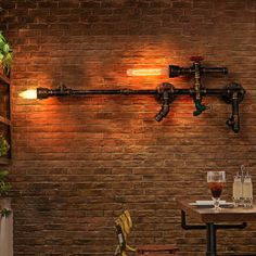 a brick wall with exposed pipes and lights on it, along with two chairs in front of the table