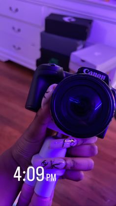 a person holding a camera in their hand with purple light on the wall behind them