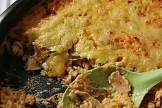 a casserole dish with meat and vegetables being stirred by a spatula on the side