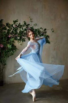 a woman in a blue dress is dancing with her arms spread out to the side