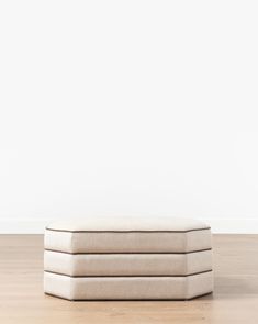 three white pillows sitting on top of each other in front of a white wall and wooden floor