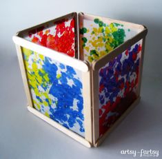 an artistic box made out of paper with paint splattered on the sides and bottom