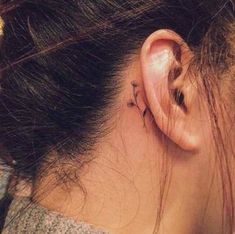 a woman's ear has a small tattoo on it