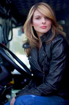 a woman sitting in the drivers seat of a truck with her hand on her hip