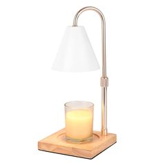 a table lamp next to a lit candle on a wooden block with a white shade