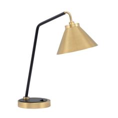 a gold and black desk lamp on a white background, with the light turned off