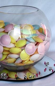 a glass bowl filled with lots of different colored candies on top of a plate