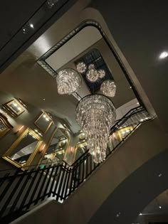 the chandeliers are hanging from the ceiling above the stairs in this modern home