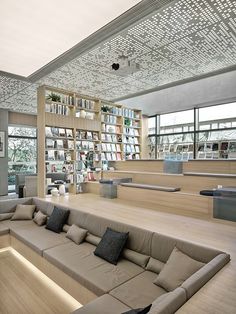 a living room filled with furniture and bookshelves next to each other in front of large windows