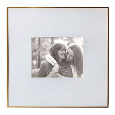 two women are hugging each other in front of a white background with gold trimming