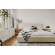 a bed with white linens and pillows in a bedroom next to a large window