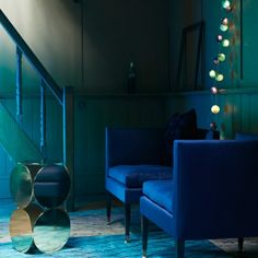 a living room filled with blue furniture next to a stair case