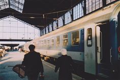 two people are walking towards a train at the station