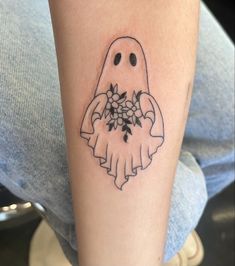 a person with a tattoo on their arm holding a bouquet of flowers and a ghost