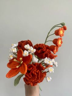 a crocheted vase filled with flowers on top of a wooden table next to a white wall