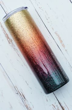 a colorful cup sitting on top of a white wooden table next to a canister