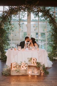 a bride and groom kissing in front of a table with candles