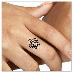 a woman's hand with a small turtle tattoo on her left ring and the other finger