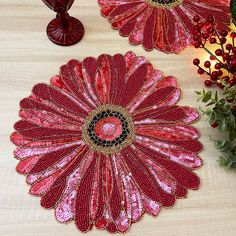 two red flower shaped place mats sitting on top of a table next to vases