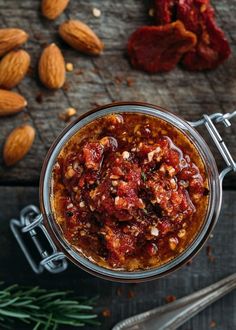 a glass jar filled with food sitting on top of a wooden table next to nuts