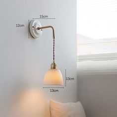 a white wall light next to a window with measurements for the lamp on it's side