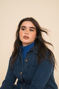 a woman sitting on top of a chair wearing a blue jacket and turtle neck sweater