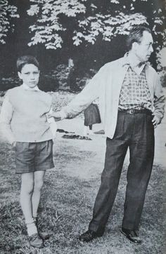 an old black and white photo of a man holding the hand of a young boy