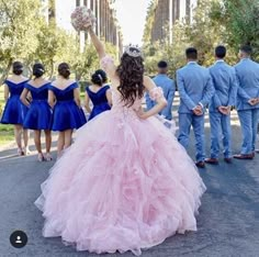 a group of people in blue and pink dresses are standing on the road with their hands up