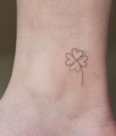 a small four leaf clover tattoo on the side of a foot with a heart in it