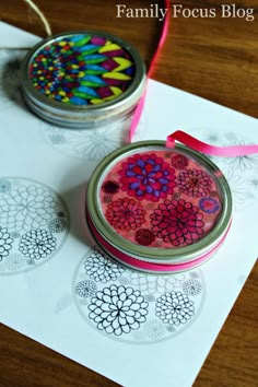 two mason jars filled with colorful flowers on top of a white paper and pink ribbon