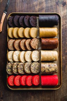 an assortment of different types of sausages in a metal tray on a wooden table