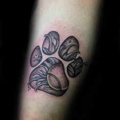 a paw tattoo with rocks and leaves on the left arm, it is black and grey