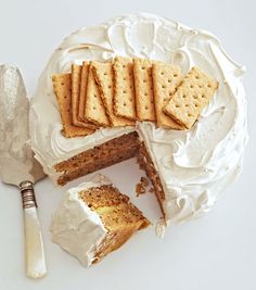 a cake with white frosting and crackers on top, next to a knife