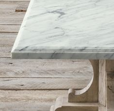 a marble topped table with wooden legs on the floor in front of wood planks