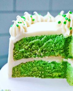 a green cake with white frosting and sprinkles