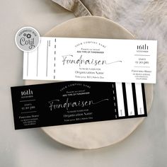 two black and white tickets sitting on top of a table next to a plate with silverware