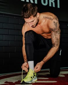 a shirtless man tying his shoe laces