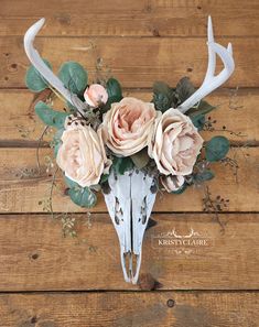 the antlers are adorned with flowers and greenery on top of wooden planks